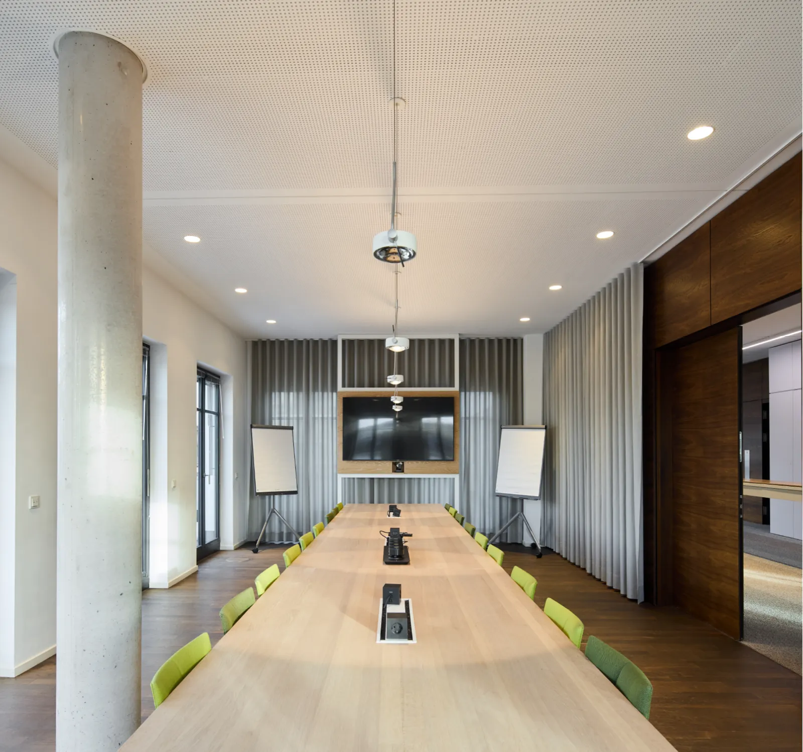 Moderner Besprechungsraum mit einer langen Holztischanordnung und grünen Stühlen im Haus A, Büroflächen Westend Ottensen, Hamburg.