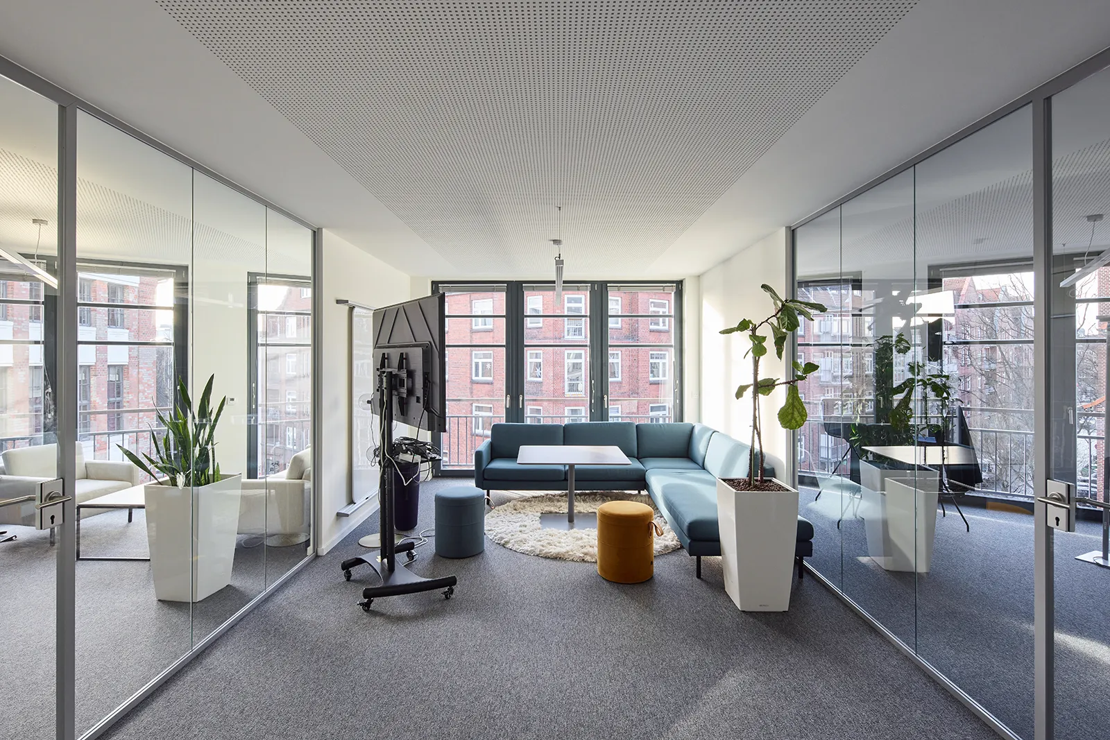 Moderne Lounge im Haus B, Büroflächen Westend Ottensen, Hamburg, mit gemütlichem Sofa und Pflanzen in einem hellen Raum.